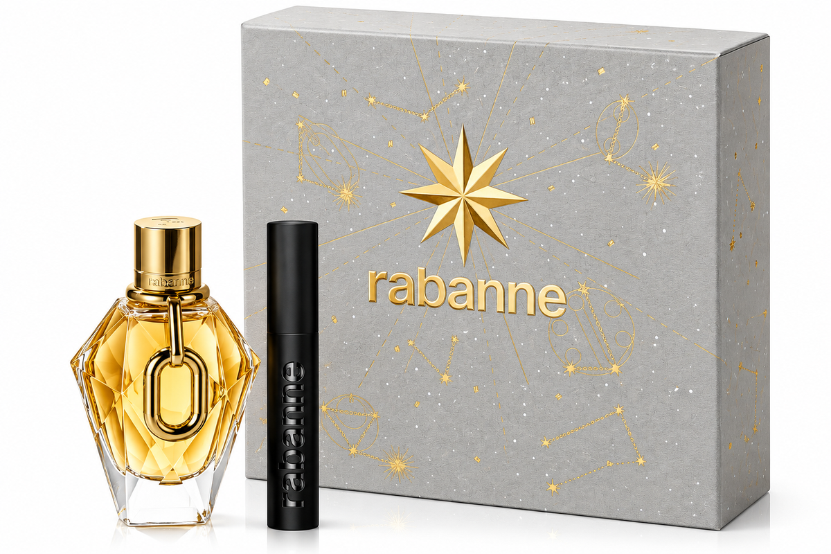 Rabanne Million Gold For Her gift set featuring the faceted golden Million Gold For Her perfume bottle and a sleek black matching travel spray, presented beside an elegant silver gift box decorated with gold celestial motifs, constellations and a prominent star. Luxurious gold detailing, distinctive Rabanne branding and premium gift-ready presentation on a clean white background.