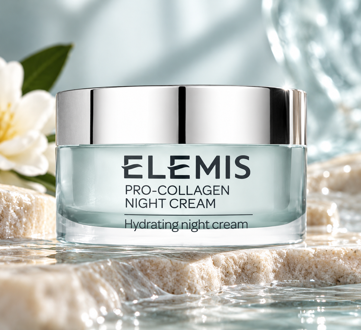 ELEMIS Pro-Collagen Night Cream in an elegant pale blue glass jar with a reflective silver lid, beautifully displayed on natural stone surrounded by delicate white flowers, fresh green leaves and flowing water. Luxurious hydrating anti-aging night cream for smoother, firmer and radiant-looking skin.