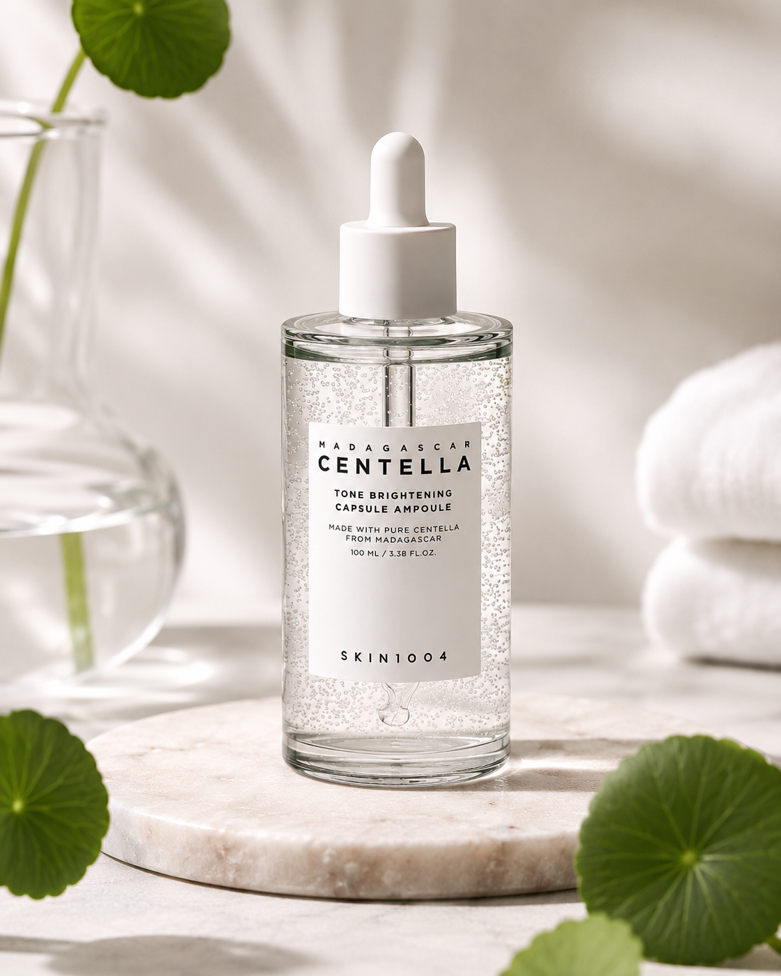 SKIN1004 Madagascar Centella Tone Brightening Capsule Ampoule 100ml  on a marble surface with green leaves and towels in the background